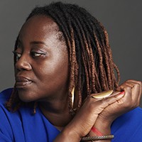 A woman with medium-length, dark hair, in a blue top, in profile. 