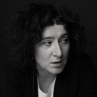 A woman with dark hair in a black and white top.