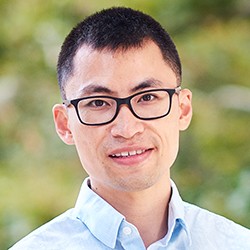 A man with short, dark hair and glasses. 