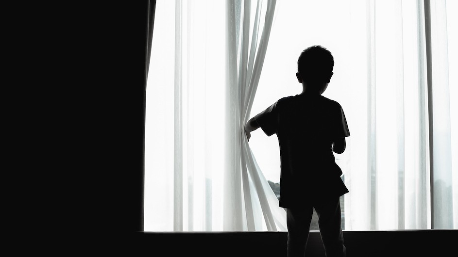 A child looks out of a curtain.