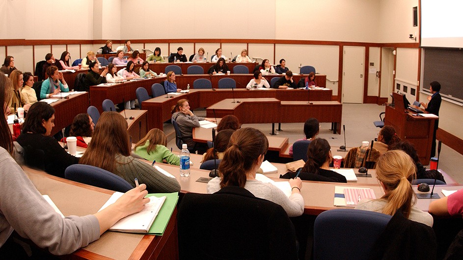 students in a classroom face a teacher.