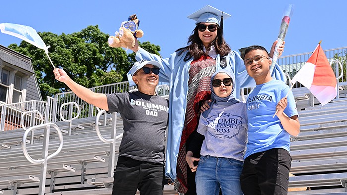 Congratulations to the whole family! Photo by Eileen Barroso. Family members surround a Columbia grad on the bleachers.
