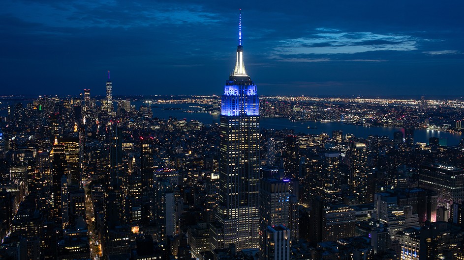 The Empire State Building, illuminated blue and white for Columbia graduates, viewed from Summit One Vanderbilt.