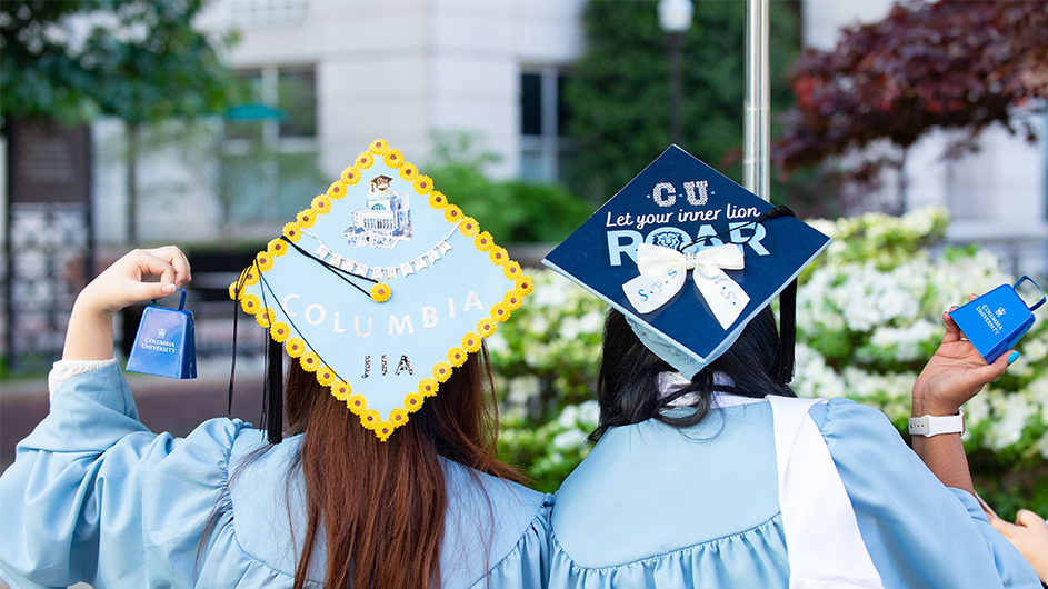 Photo by Diane Bondareff. Two graduates show off their decorated grad caps at Columbia Commencement 2023.
