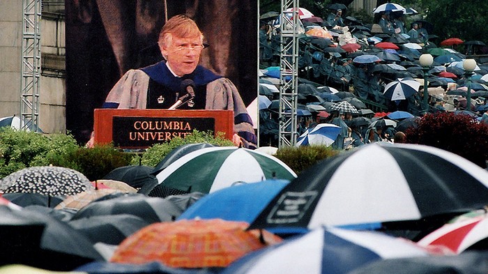 2003 photo by Eileen Barroso. President Bollinger on the jumbotron at his first commencement amidst a sea of umbrellas.