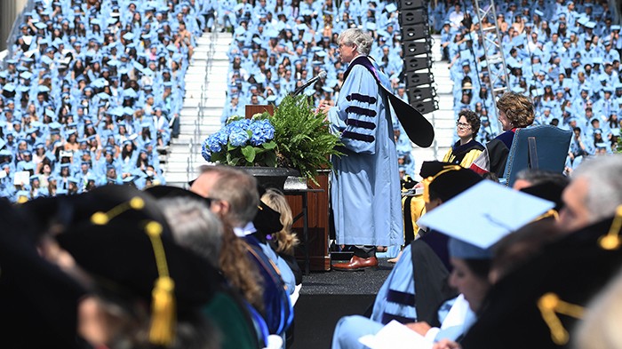 2022 photo by Eileen Barroso. President Bollinger addresses the crowd as his cape flows behind his back.