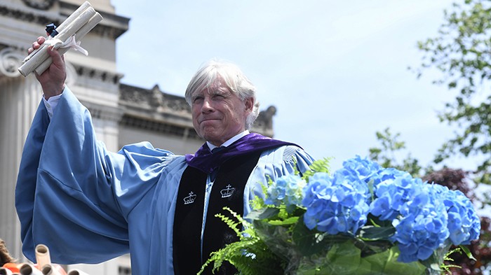 2022 photo by Eileen Barroso. Bollinger holds up diplomas in front of Low Library.