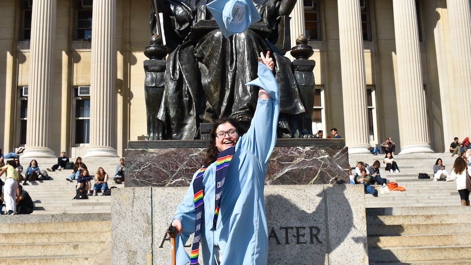 Leslie Zukor (JRN'23) on Low steps in front of the statue of Alma, wearing her Disability Affinity Graduation celebration stole. Photo credit: Caroline Harting Leslie Zukor, (JRN'23) in her commencement regalia on the steps of Low Library in front of the statue of Alma throwing her mortar in the air.
