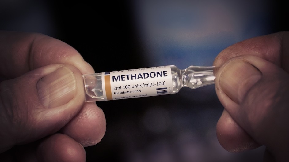 A person holding a methadone vial.
