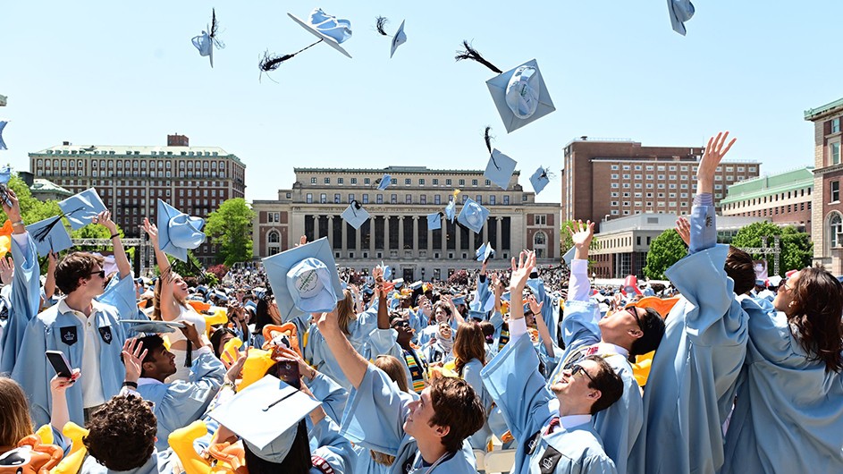 Columbia graduates throw mortar boards in the air. 