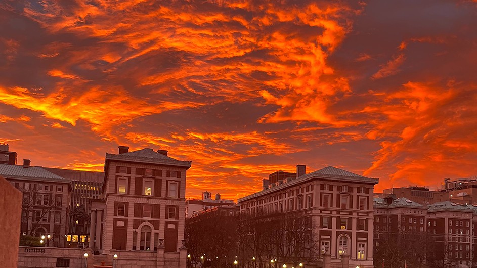 Low Plaza, Kent Hall, and Hamilton Hall against a cloudy orange sky during sunrise at Columbia University.