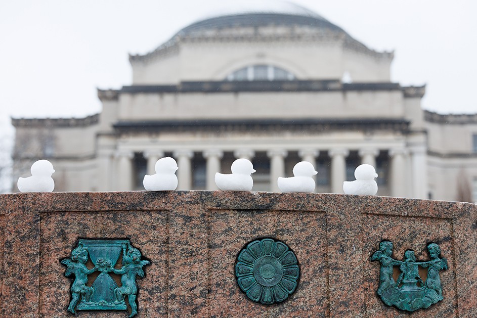 Five snow duck peeps on the Sundial sculpture with Low Library in the background on a cloudy winter day at Columbia University.
