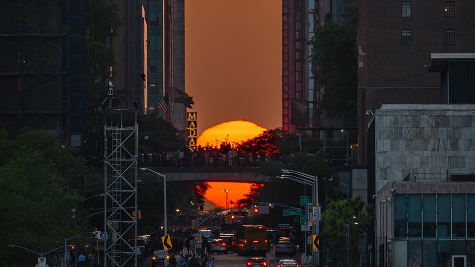 The sun setting on 42 Street between tall buildings in New York City during Manhattanhenge.