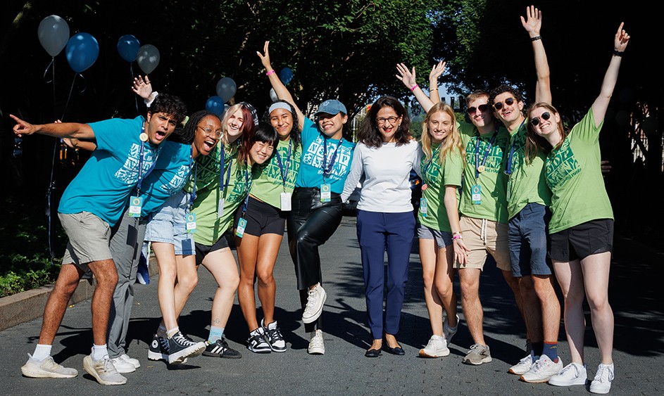 Ten students with Columbia President Minouche Shafik smile and cheer as they welcome new students to Columbia University.