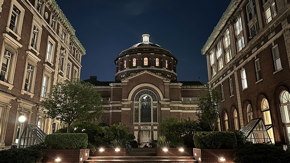 St. Paul's Chapel with illuminated windows at night alongside Avery Hall and Fayerweather Hall at Columbia University.