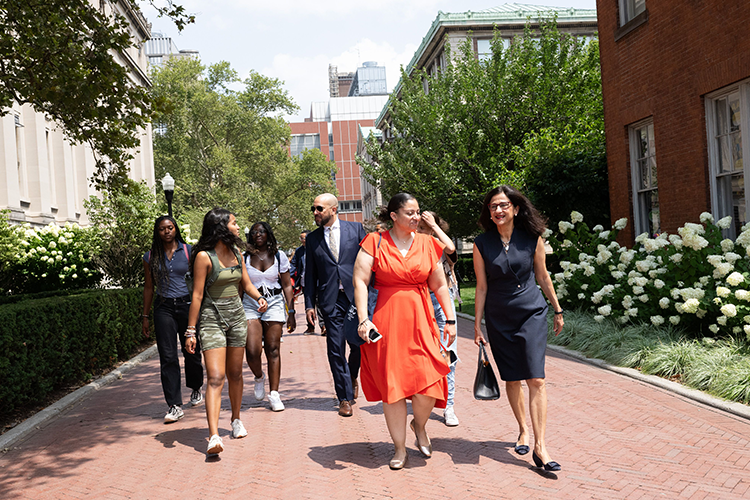 Double Discovery Center students, Columbia College Dean Josef Sorett, DDC Executive Director Sasha Wells, and President Minouche Shafik walk through Columbia's campus on a sunny day. 