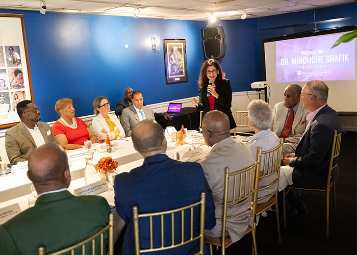 President Minouche Shafik addresses a group sitting around a table. 