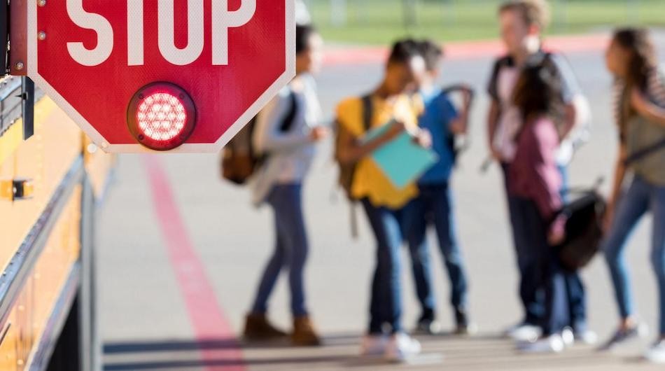 Students gather near a school bus