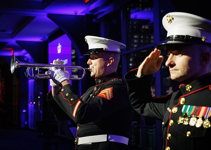 The honor and service of our veterans is just one of the things that makes the Columbia community stand proud. Photo by Sirin Samman. A trumpeter in dress blues plays as another service member with a chest full of honors salutes.