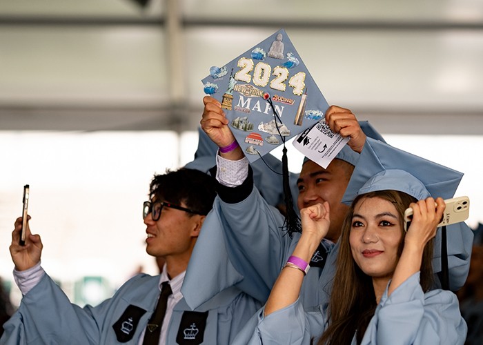 Graduates of the Graduate School of Arts and Sciences show off a mortar board festooned with joyous decor. Photo by Jahsie Ault. Graduates School of Arts and Sciences students celebrate.