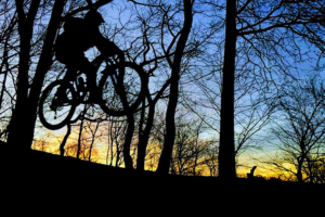 Yanev hitting the trails at Highbridge Park. He volunteers to maintain this trail and others with the NYC Mountain Bike Association. Back-lit image of Yanev riding a mountain bike at Sunset.