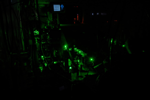 The experimental set-up at the Borys Lab at the University of Montana, which specializes in low-temperature optics and has been a long-time collaborator with the Schuck Lab. Green lasers on an optical table.