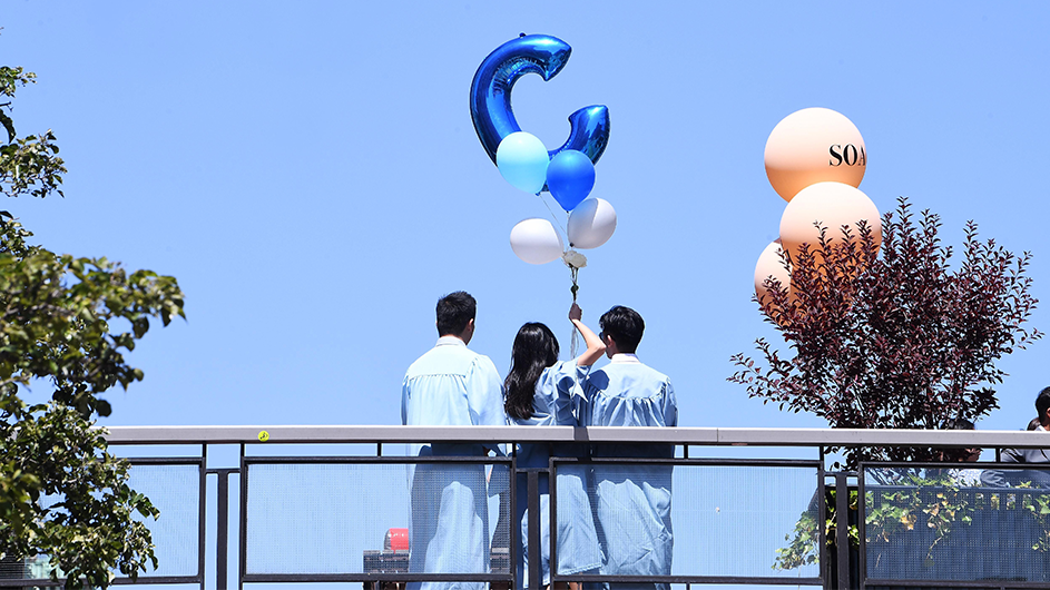 Graduates hold a balloon in the shape of a "C"