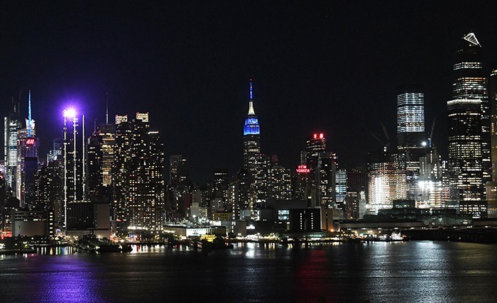 The New York City skyline as seen from New Jersey with the Empire State Building lit blue.
