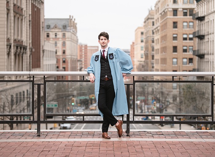 A graduate poses on Revson Plaza overlooking Amsterdam.