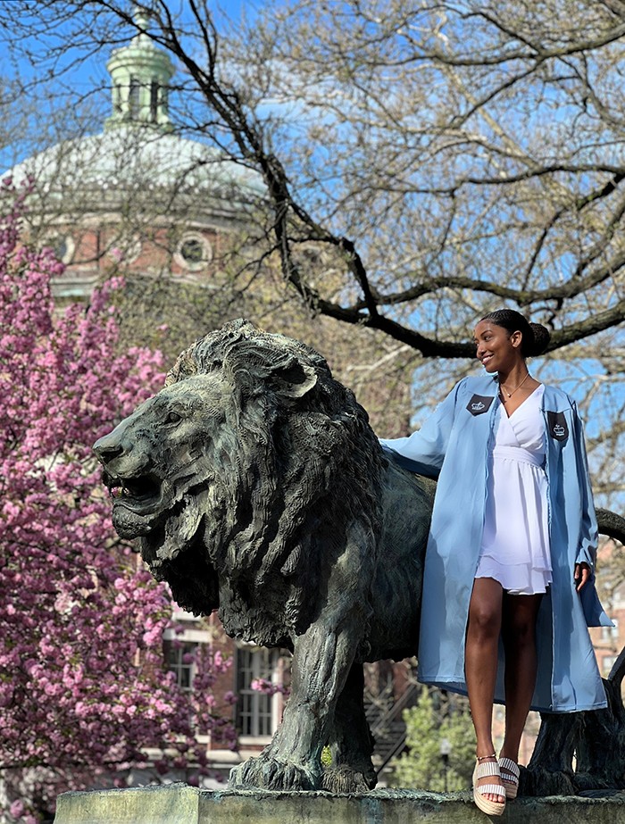 A grad stands with Scholars Lion.