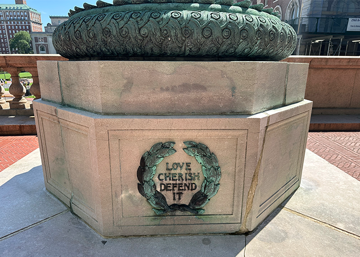 The inscription at the base of the western flagpole reads "Love Cherish Defend It." Photo by Kelly Moffitt-Hawasly. "Love. Cherish. Defend it." reads an inscription at the base of a flag pole.
