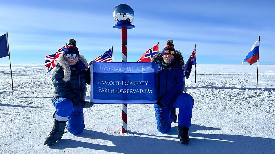 Mission Spiritus Antarctica polar explorers Alan Chambers and Dave Thomas raise a Columbia Climate School Lamont-Doherty Earth Observatory flag as they pose at the South Pole after completing their polar ice trek.