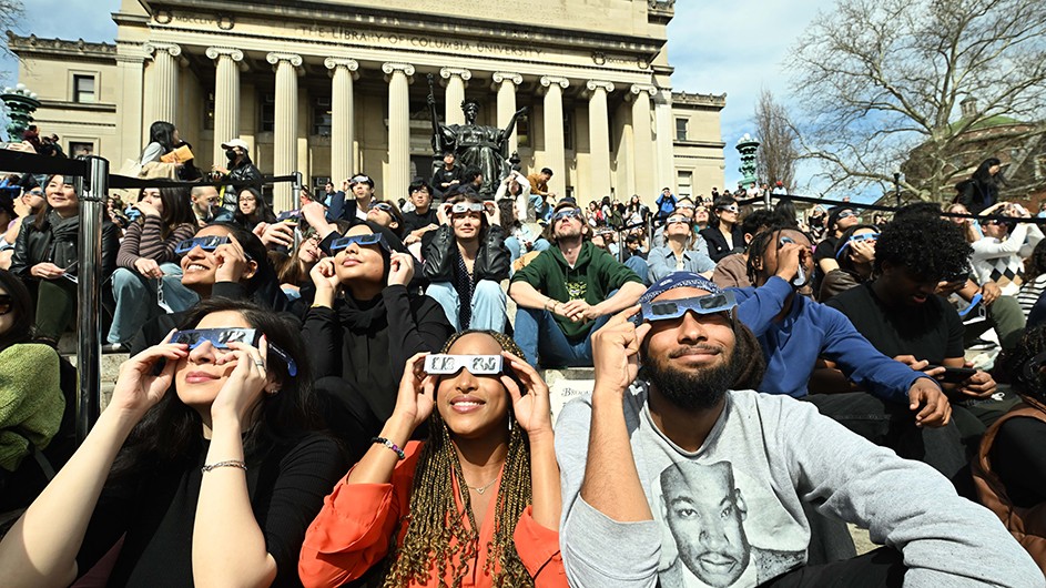 Columbians wearing eclipse glasses gather on Low Steps on Monday, April 8, 2024, to view the partial solar eclipse at Columbia University.