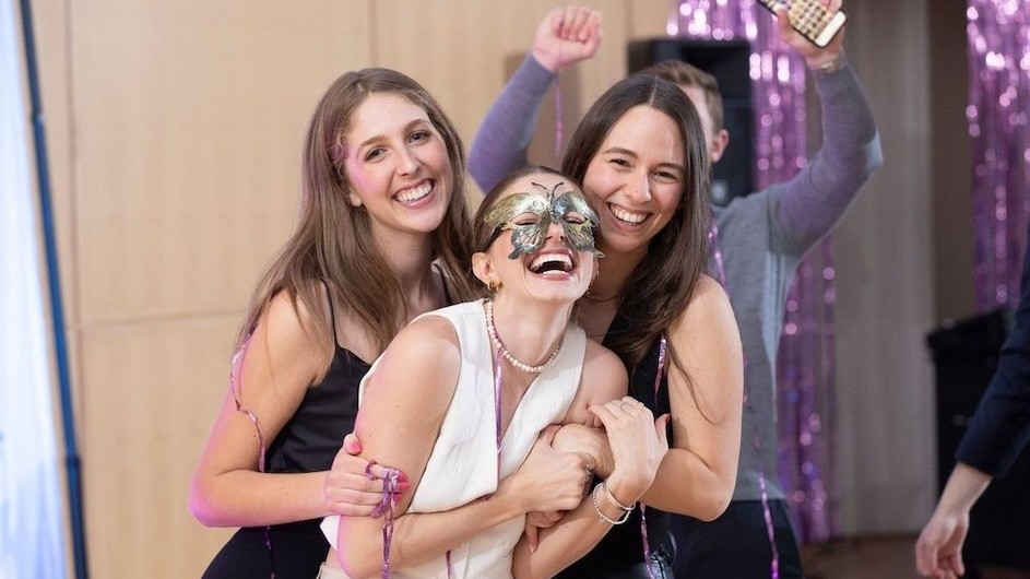 Three students at a masquerade dance to kick off Purim celebrations at Columbia