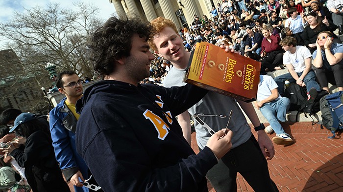 A Columbia student views the eclipse through a camera obscura, constructed using a Cheerios box.