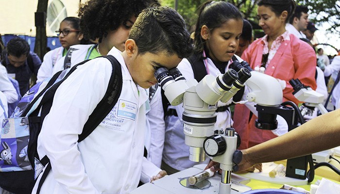 Photo by Katherine Rojas/CUIMC. A kid looks through a microscope at a curiosity cube event