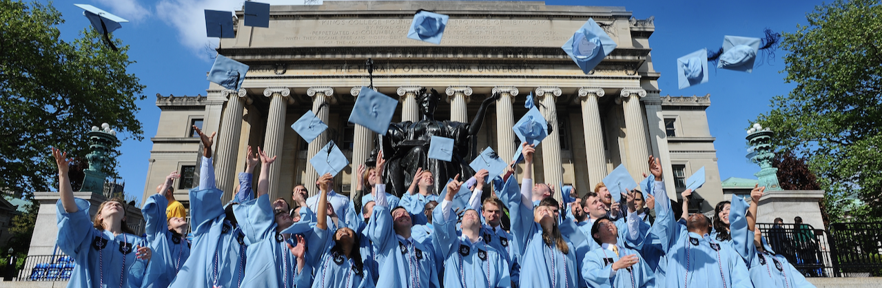 Columbia Military Veterans in graduation gowns toss their caps in front of Low Library
