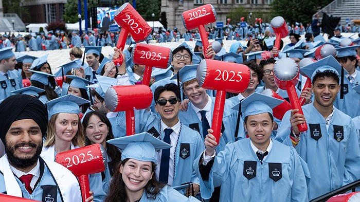 Graduates of Columbia Engineering wave their iconic inflatable hammers while cheering at Commencement. Photo by April Renae. Columbia Engineering students hold up inflatable red hammers with "2025" emblazoned on them.