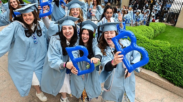 Barnard College grads crossed Broadway to make their entrance to Commencement. Photo by Chris Taggart. Barnard College grads cross Broadway holding Barnard "B" balloons.