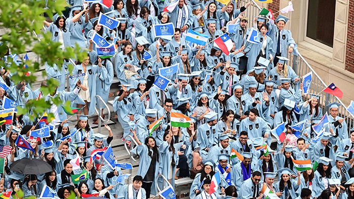 Graduates of the School of International and Public Affairs wave flags during Commencement. Photo by Chris Taggart. SIPA graduates waves flags at Commencement.