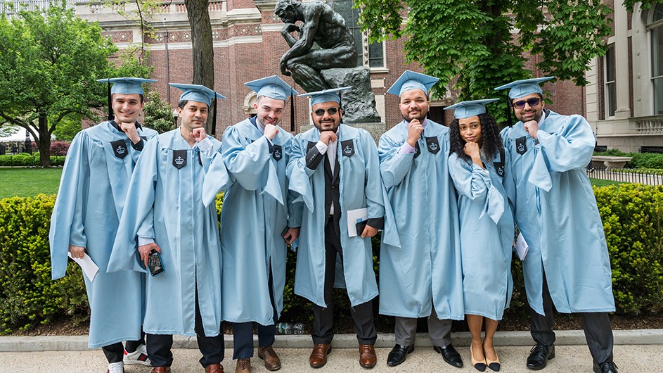A group of university graduates poses in front of The Thinker statue at Columbia University.