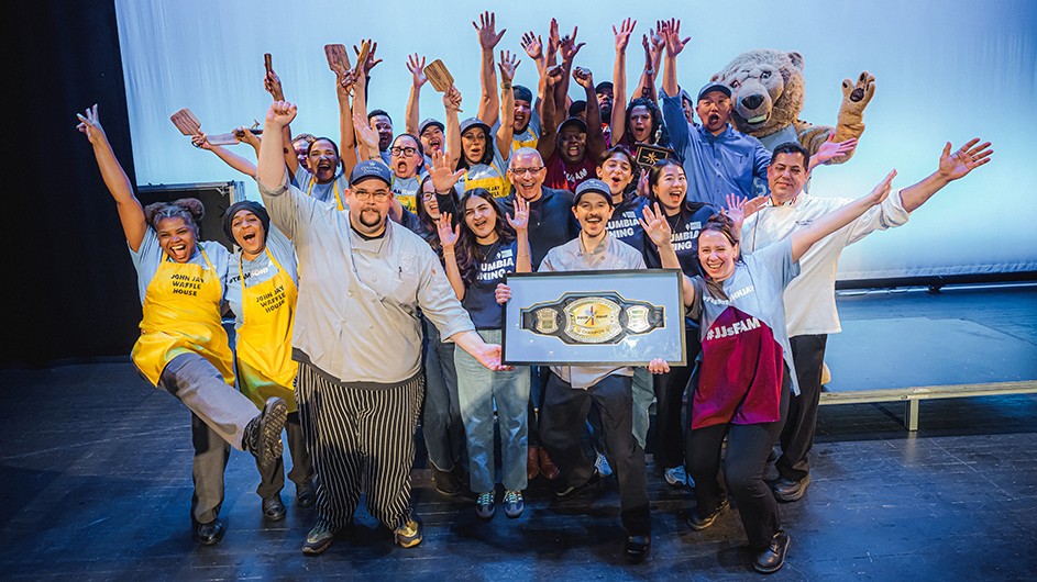 Several university students, lion mascot, chefs, and dining staff members celebrate and pose with dining awards for two top prizes in Battle of the Dining Halls at Columbia University.