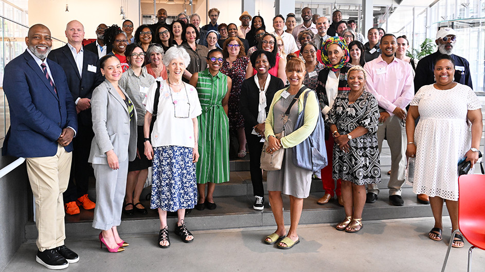 Dozens of Columbia Community Service grantees smile and pose for the camera in the lobby of The Lee C. Bollinger Forum at Columbia's Manhattanville campus. 
