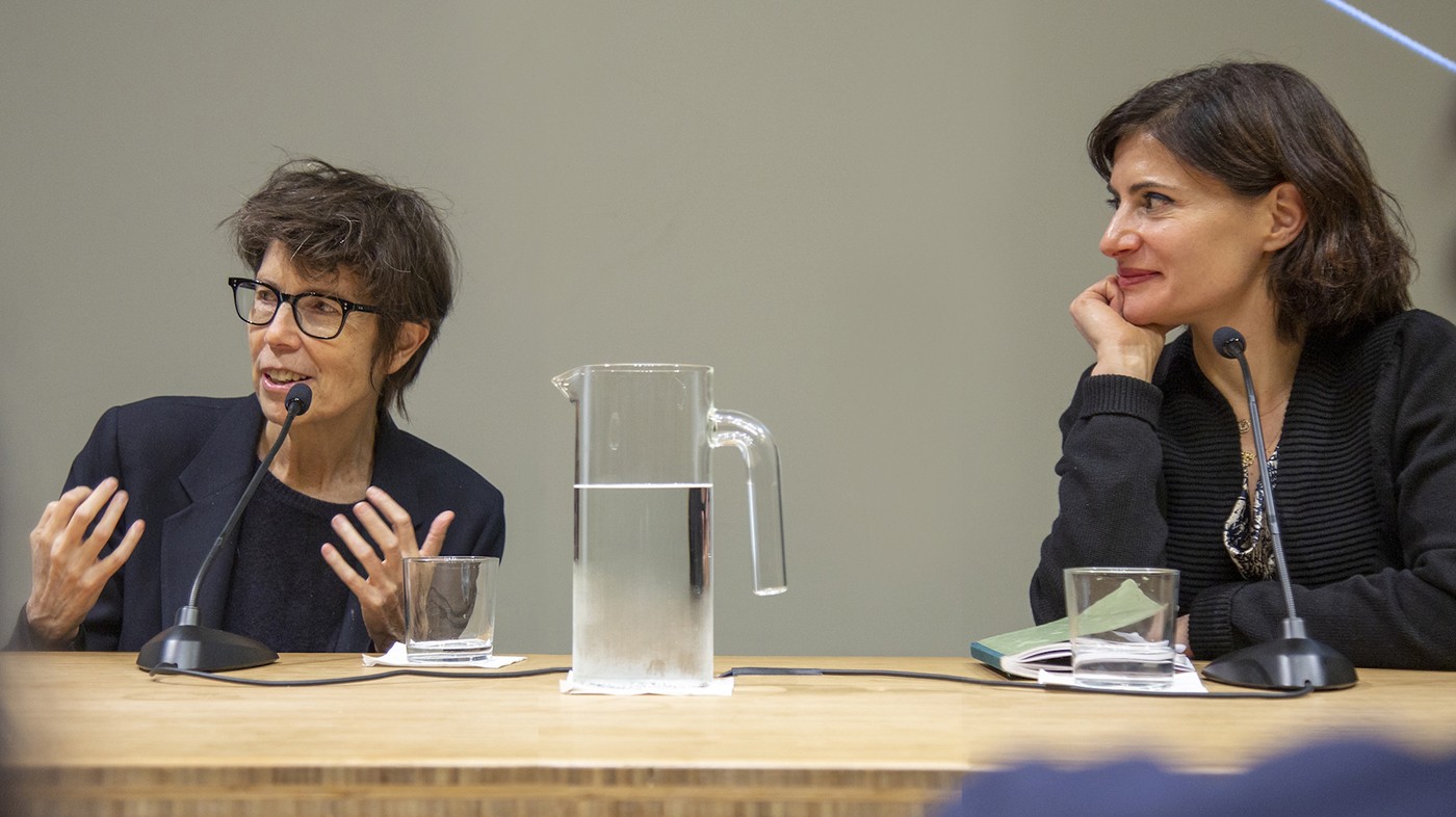 On the left, architect Elizabeth Diller; on the right, Amale Andraos, dean of the Graduate School of Architecture, Planning and Preservation. Two women seated at a table with a glass pitcher of water between them.