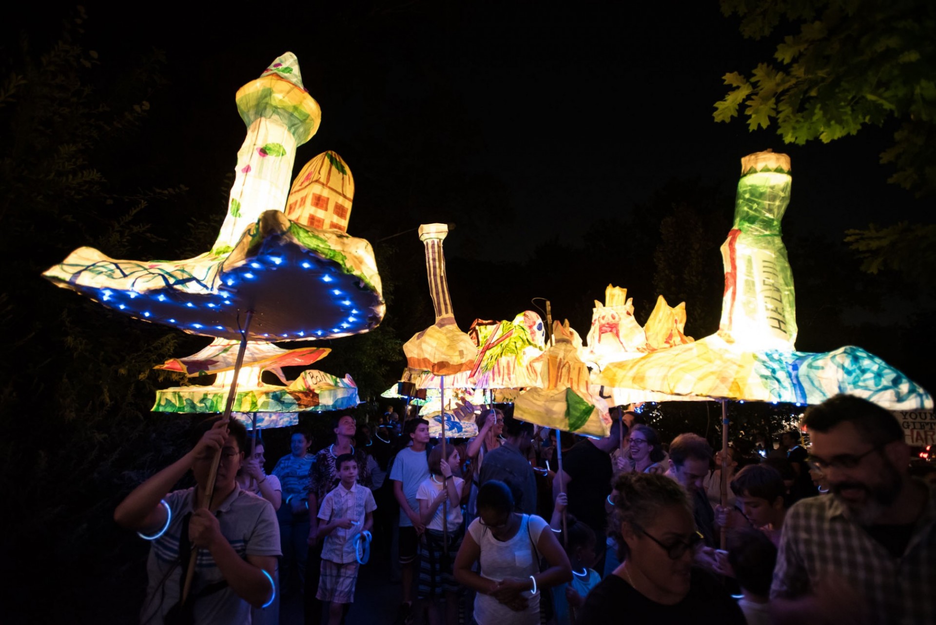 A crowd of people at night holding lit lanterns.