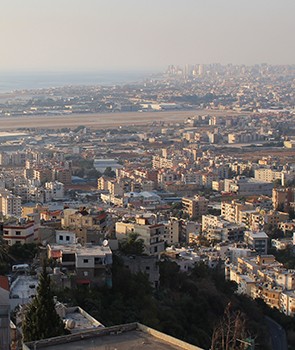 A cityscape with sky and water in the distance.