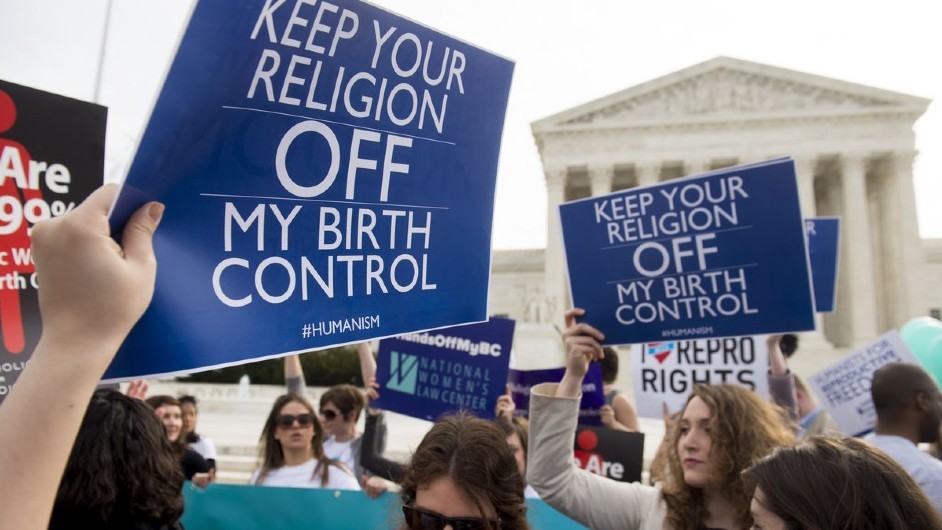 Women holding up protest signs that say keep your religion off my birth control