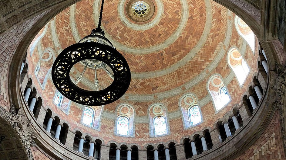 The ceiling tiles and windows of the 91-foot-tall vault of St. Paul's Chapel on campus sparkle after the building's recent restoration. A view looking up into the interior bricked dome of a church.
