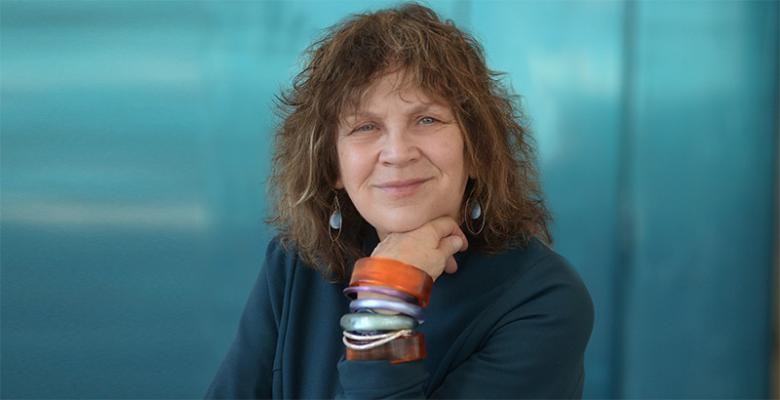 photo by Eileen Barroso Image of Carol Becker wearing a dark blazer hand underneath chin while wearing multi colored bracelets