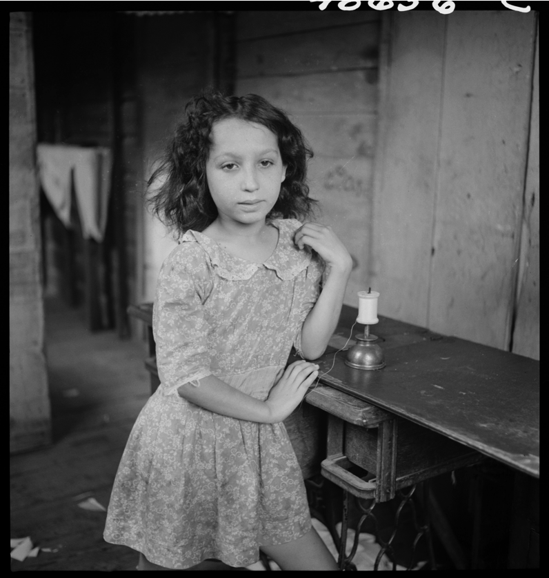 A girl stands by a sewing table with a roll of string. Photo Courtesy of the Delano Collection at Rare Book and Manuscript Library